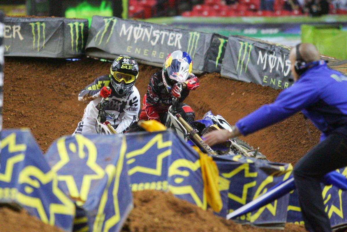 Chad Reed and James Stewart wrestle to get their bikes back up.