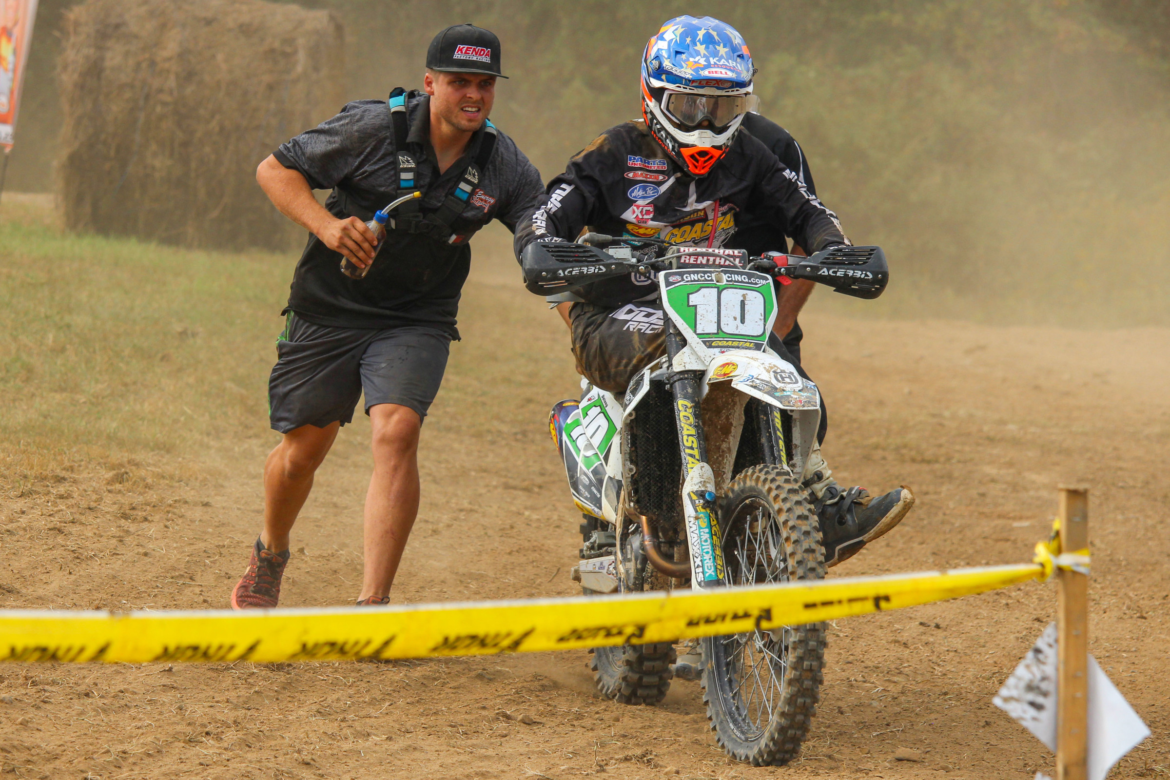 After mechanical issues ended Stew Baylor's day, he started helping out Craig DeLong (here pushing to bump start DeLong bike) and company under at the Coastal Racing/Husqvarna tent.