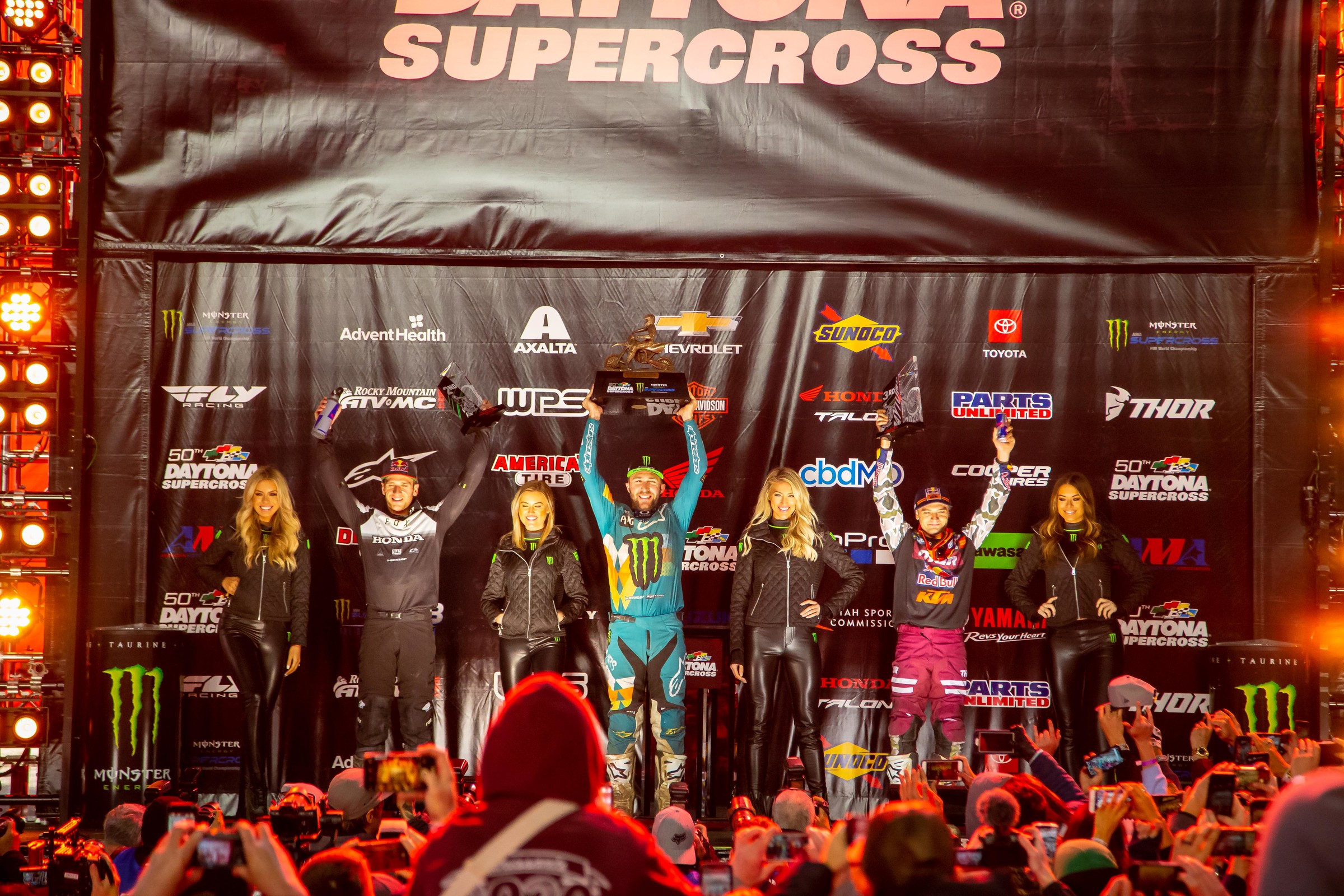 The Daytona Supercross 450SX main event podium: Ken Roczen (second), Eli Tomac (first), and Cooper Webb (third).