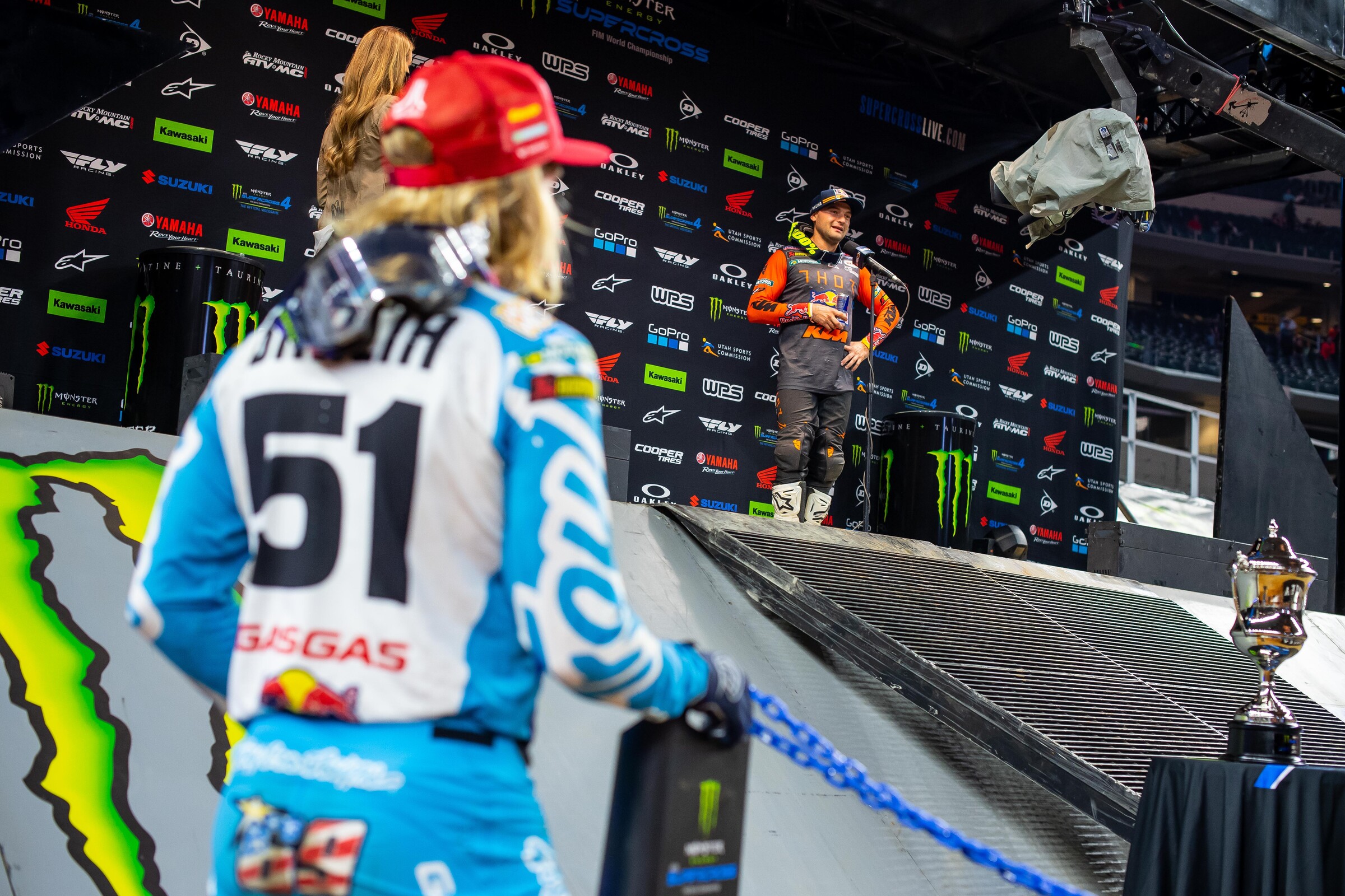 Justin Barcia walks by as Cooper Webb does his TV interview.