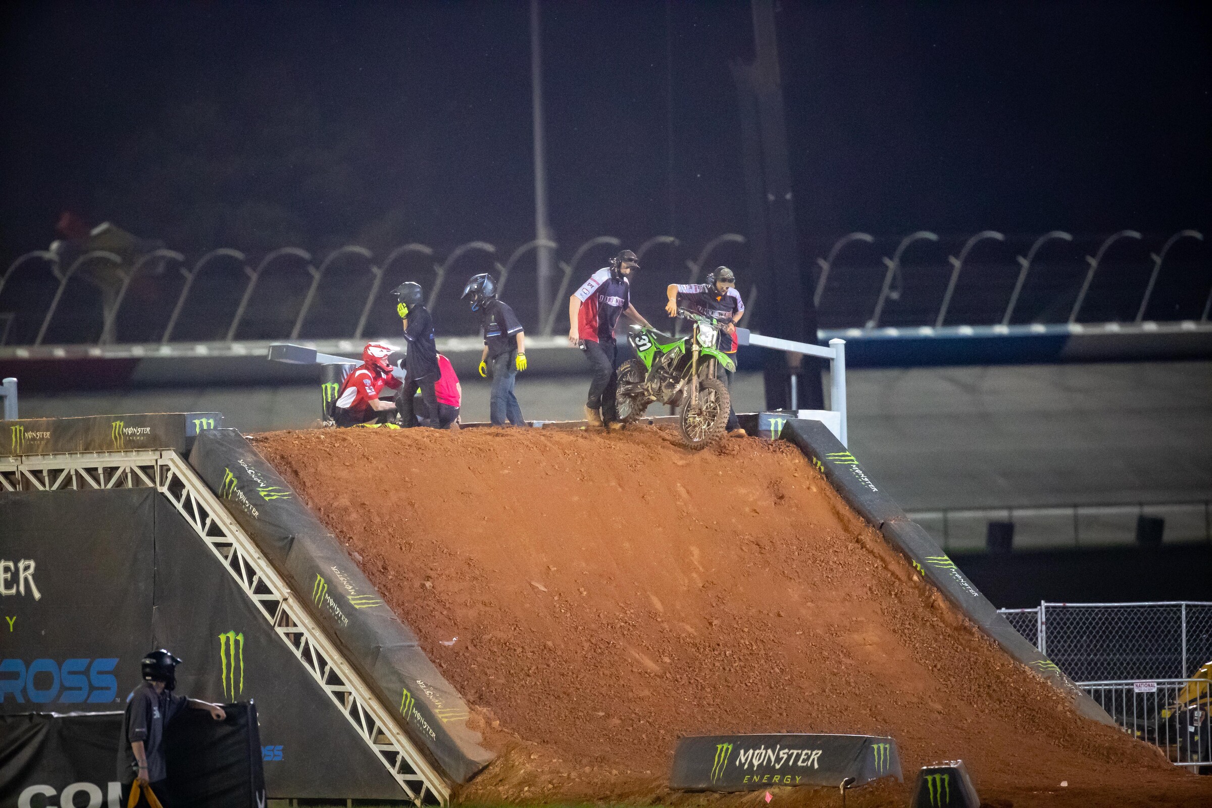 Dirt Wurx crew members removing McAdoo's Kawasaki KX250 from the track as the Alpinestars Medical Crew tends to McAdoo.