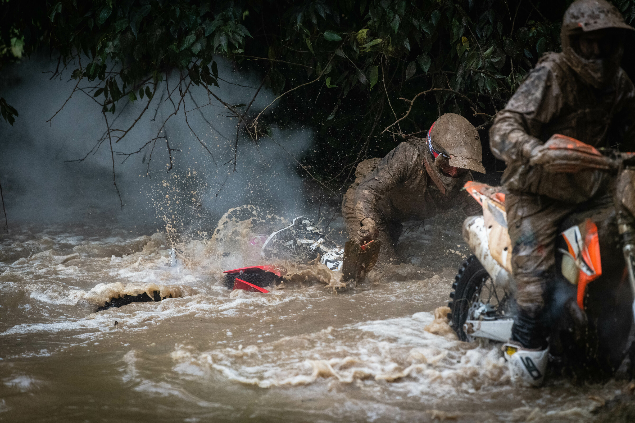 Ricky Russell cleaning off his GasGas in the creek-turned-river crossing.