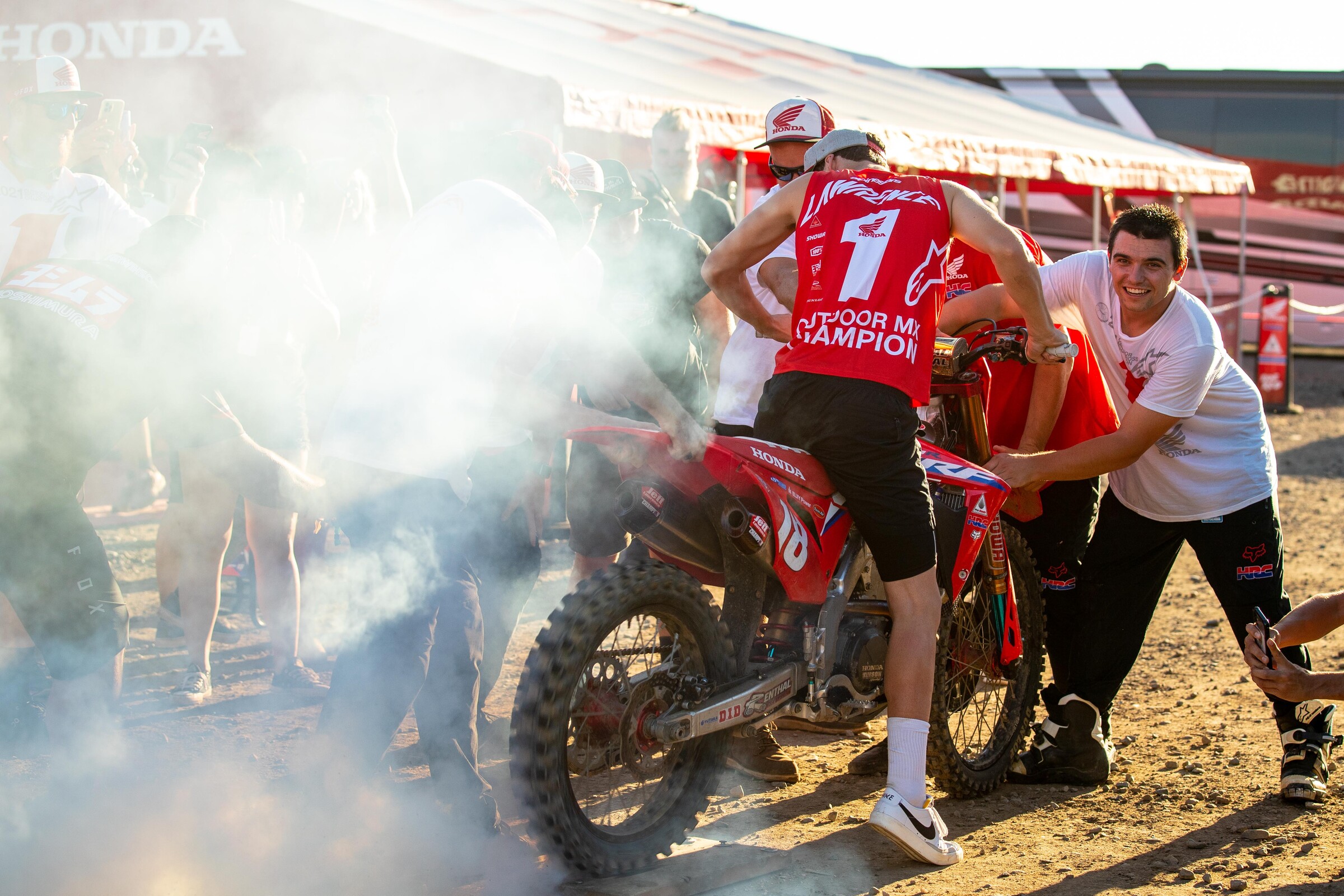 Christien Ducharme holding Jett Lawrence's CRF250R during some celebratory burnouts after Lawrence won the 2021 Lucas Oil 250 Pro Motocross Championship.