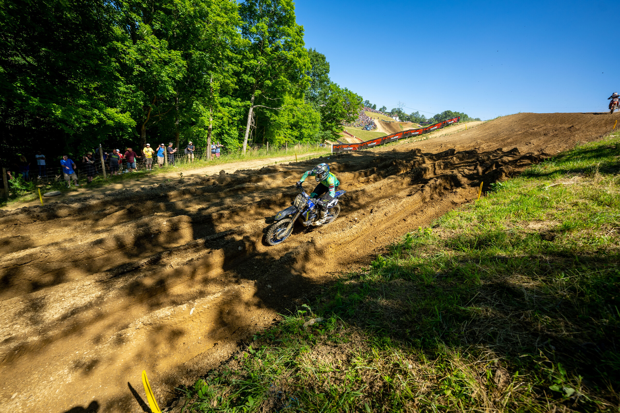 Eli Tomac taking the shorter way around the track in a very rutted/rough corner.