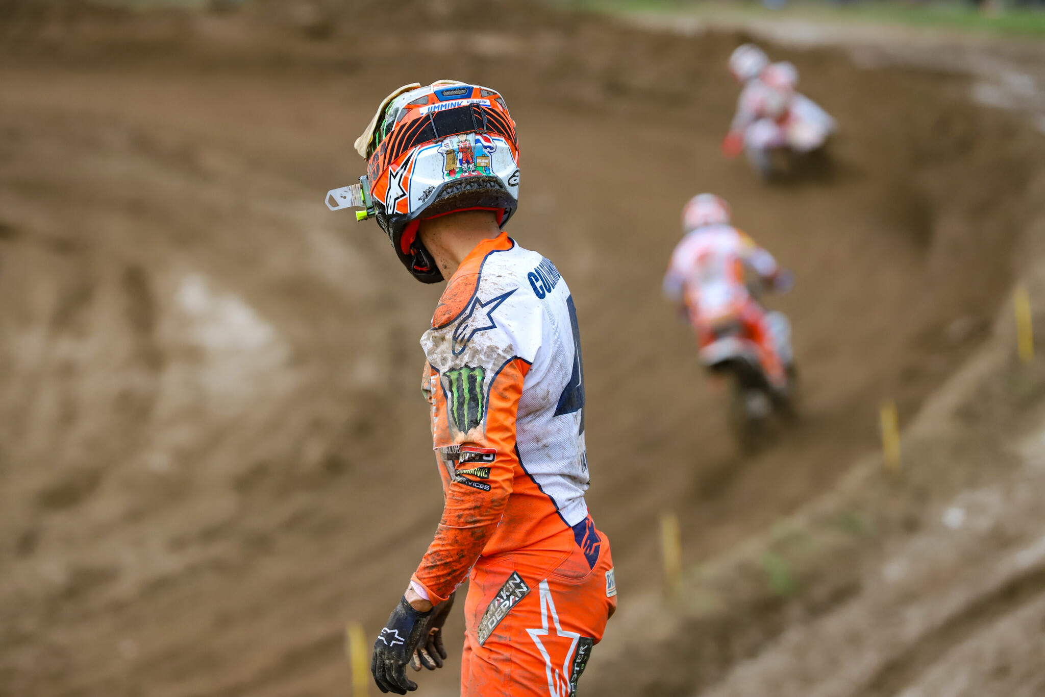 Glenn Coldenhoff watches the action as he walks alongside the track on the water truck road after his bike gave out in the third and final moto of the day.