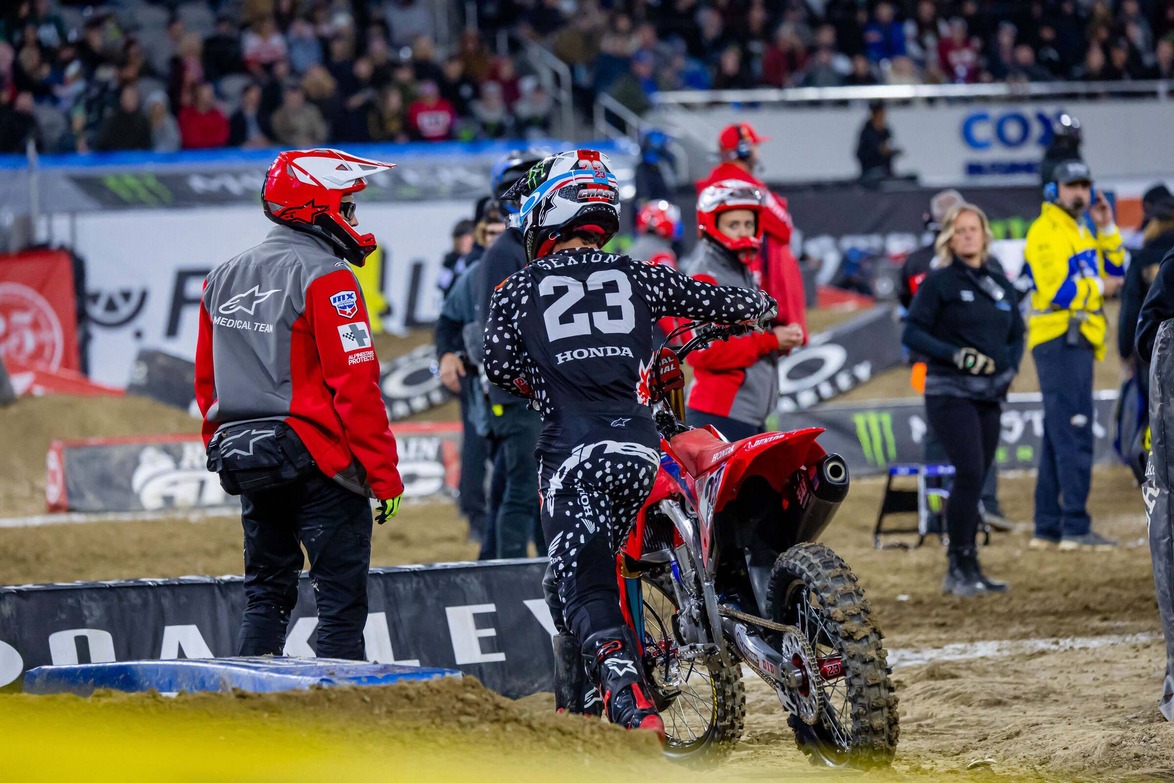 Chase Sexton pushing his bike back to the mechanics' area after a crash in his heat race left him with a smashed in gas tank.