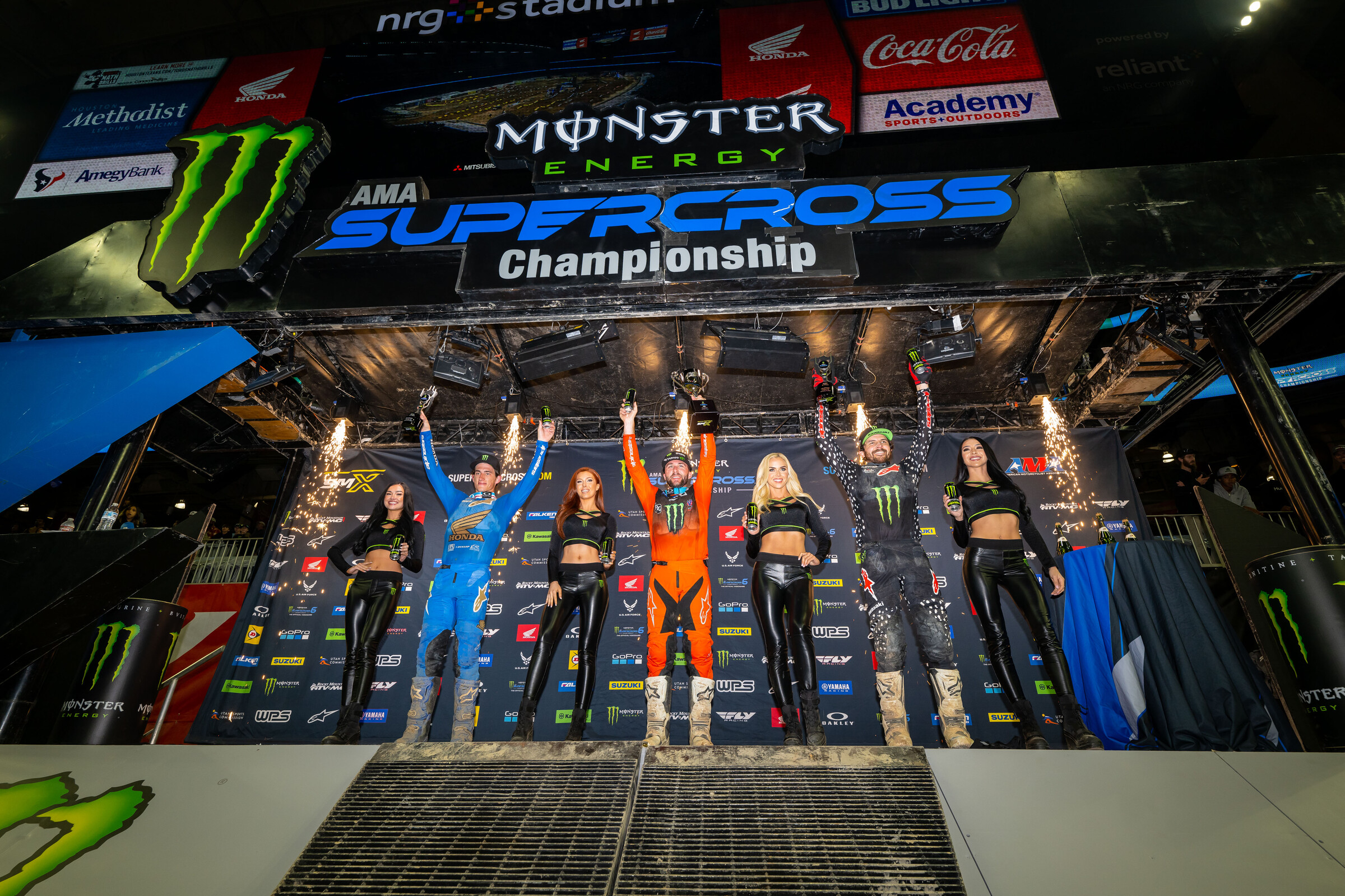 The 2023 Houston Supercross 450SX main event podium: Eli Tomac (Yamaha), Chase Sexton (Honda), and Jason Anderson (Kawasaki).